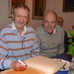 Oss skidkungar emellan, Pertti Varis skriver i den 70-åriga gästboken. Karl-Olof Johansson, själv känd välskrivare och skidåkare kollar snitsen på namnteckningen.