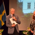 Jan Wickström tackar för byggnadsvårdspriset med Viksbo projicerad på väggen bakom. Jans syster Inga och hennes make Bo Ekström lyssnar.