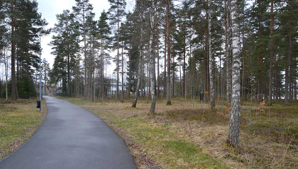 Mellan träden skymtar Fenix. Förskolan Växthuset ligger öster om cykelvägen. 